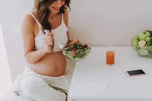 Hier sieht man eine schwangere Frau, die sich gesund ernährt