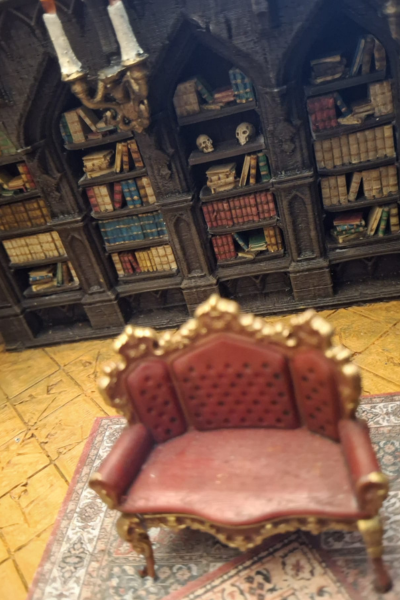Rotes Miniatursofa vor Bücherwand im viktorianischen Stil