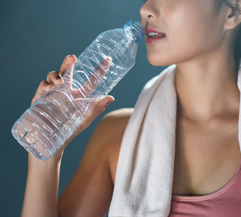 Frau trinkt Wasser aus Plastikflasche nach Sport Flüssigkeit als Fundament der Ernährungspyramide