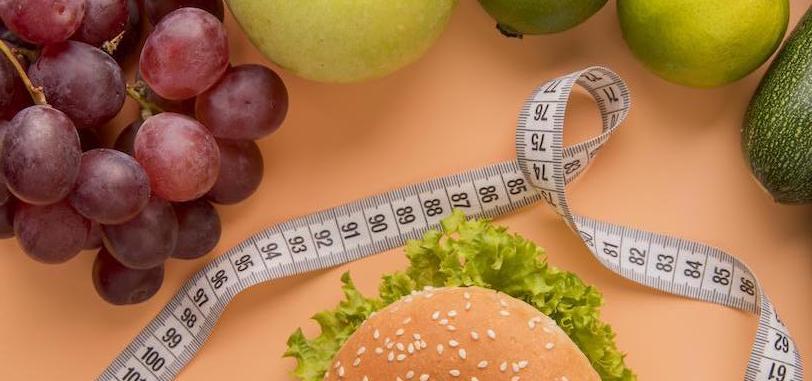 gesundes essen und ungesundes essen fürchte und hamburger auf dem tisch durch maßband getrennt