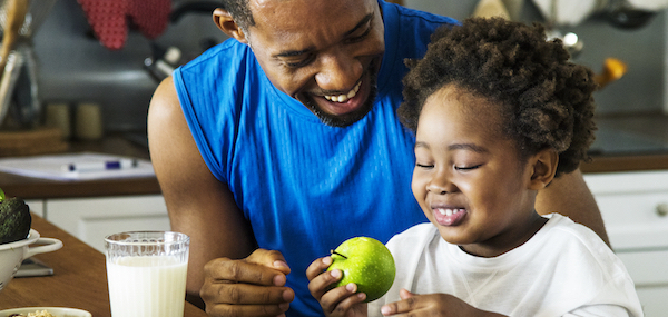 Vater und Sohn in der Küche lachen und essen saure Lebensmittel zur gesunden Ernährung