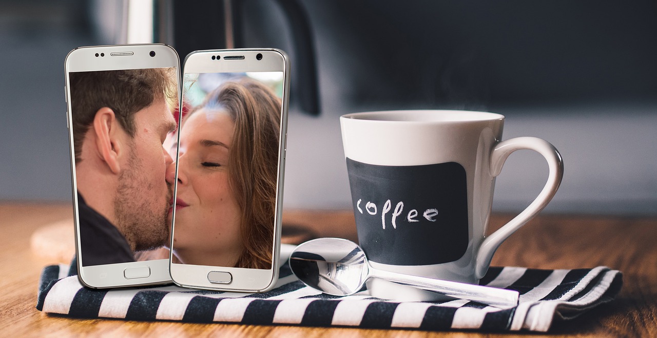 Zwei Handys mit Mann und Frau auf dem Screen, die sich küssen