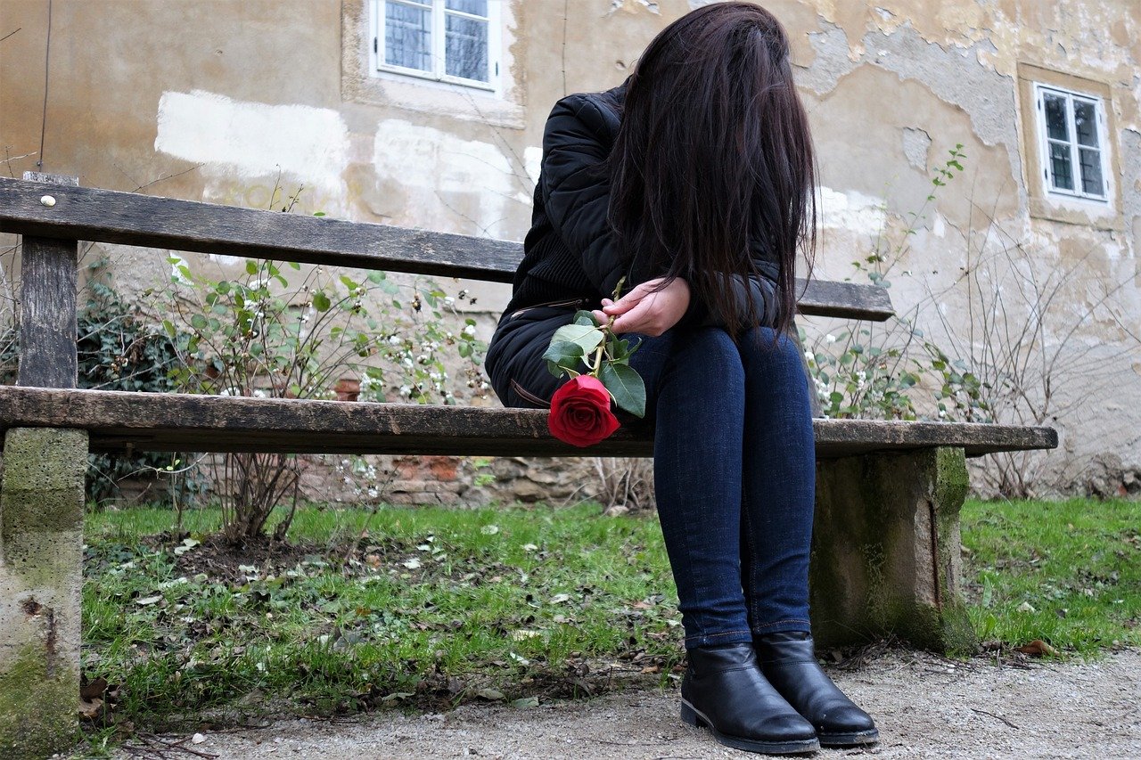 Trauriges Mädchen mit roter Rose