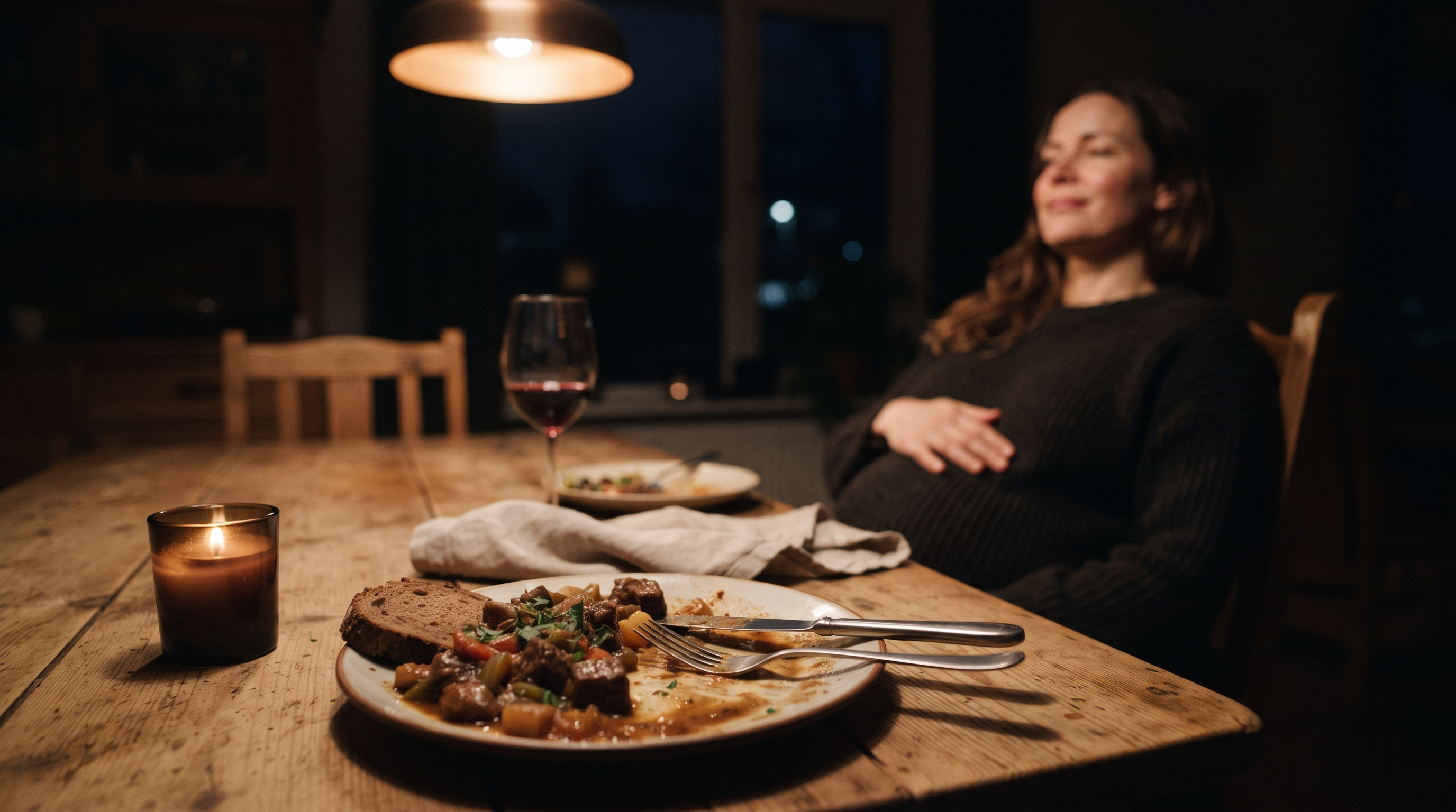 Halb voller Teller mit einem schweren Abendessen spät am Abend auf einem Holztisch