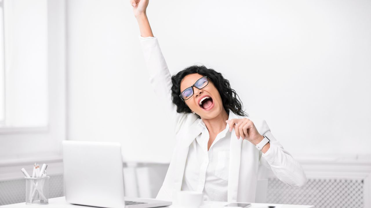 Frau im Büro vor weißem Hintergrund freut sich.