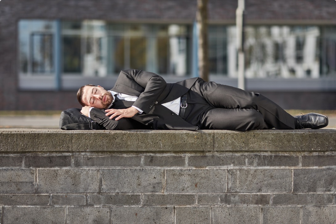 Manager schläft auf Mauer.jpg