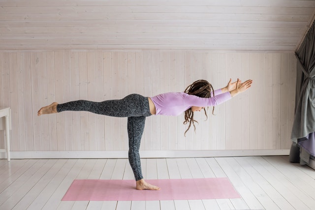 Frau auf Matte übt Bikram Yoga
