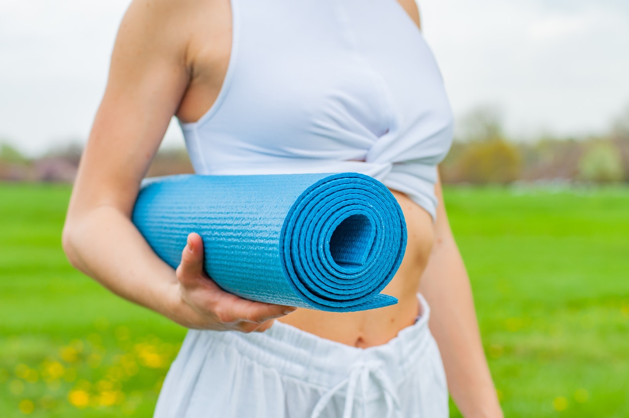 Frau hält Yogamatte im Arm