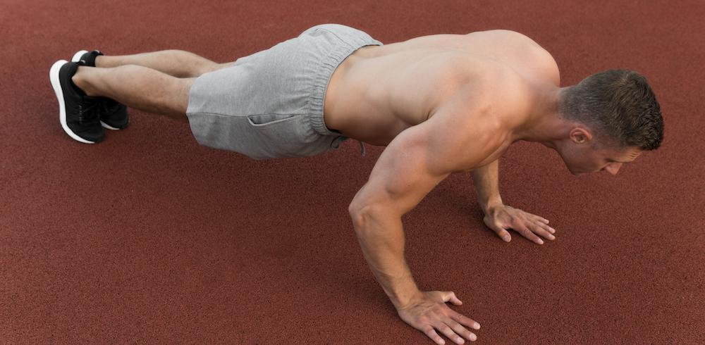 sportlicher mann macht Liegestütze auf rotem Boden