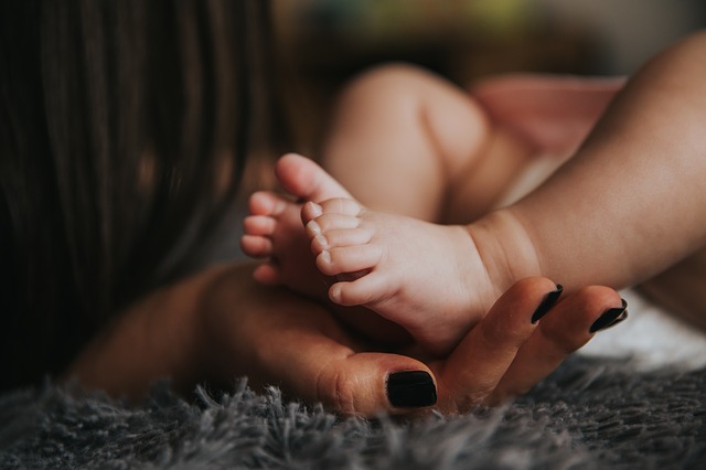 Mutter hält die Füße Ihres Neugeborenen