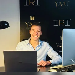 Mitarbeiter des YAVU® Support-Teams am Laptop vor der IRI® Fotowand